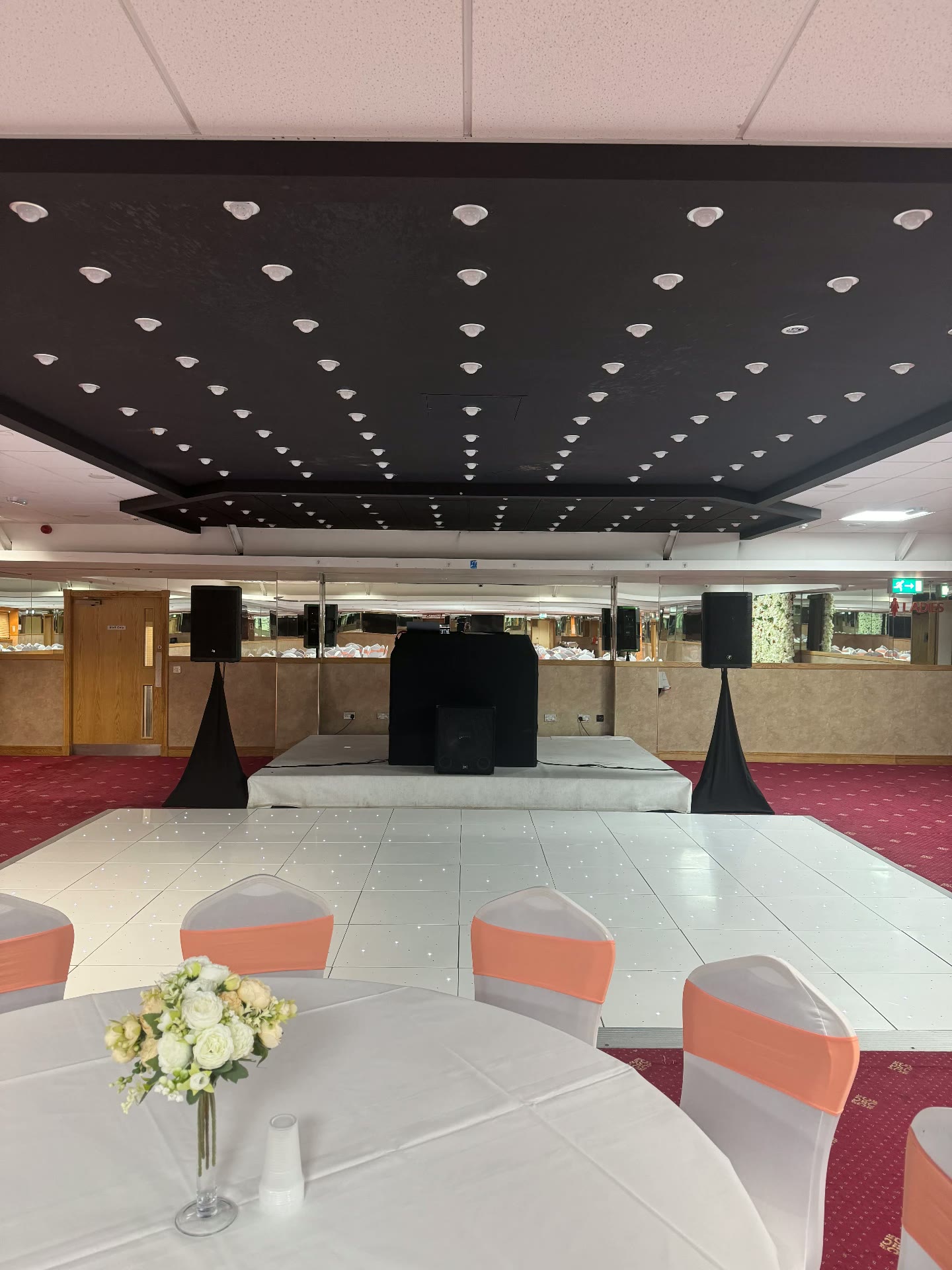White starlit LED dance floor with DJ booth, speakers and dressed wedding tables