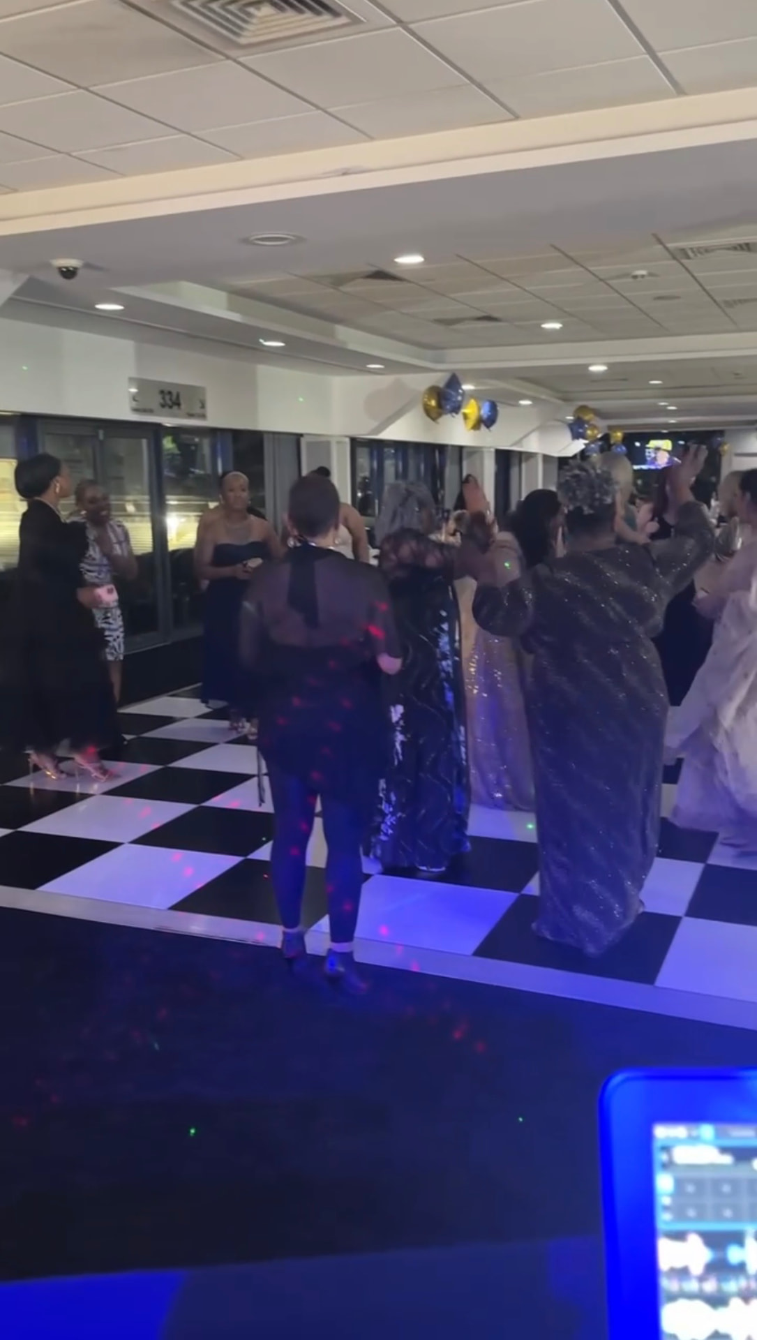 Guests dancing on a black-and-white checked dancefloor with disco lighting