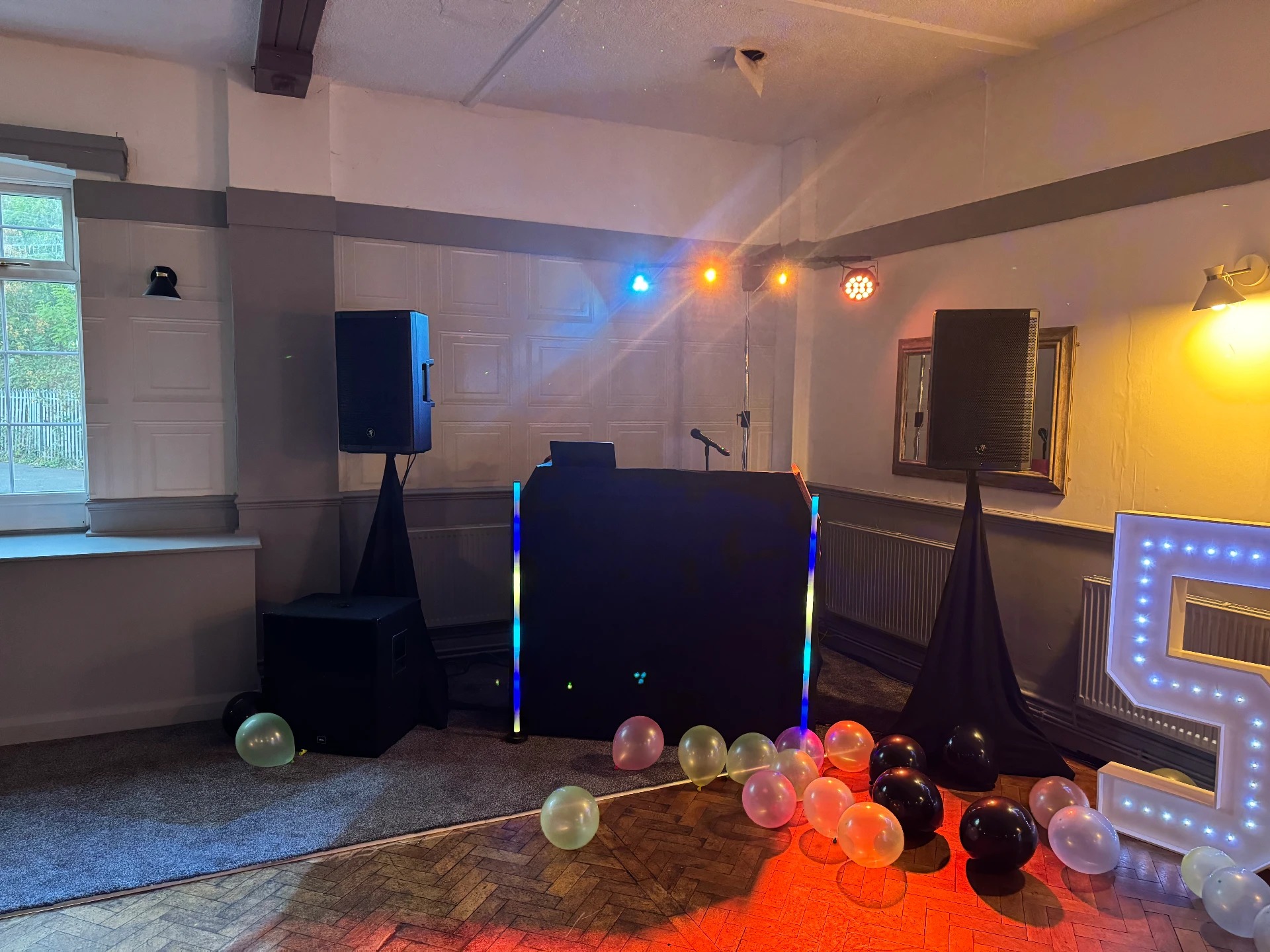 DJ booth with speakers, uplighting, LED letters and balloon decor