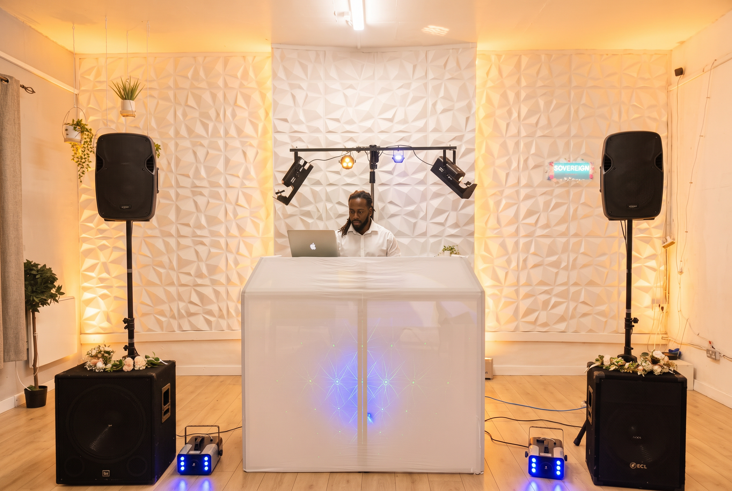 Warm-lit wedding DJ setup with uplighting