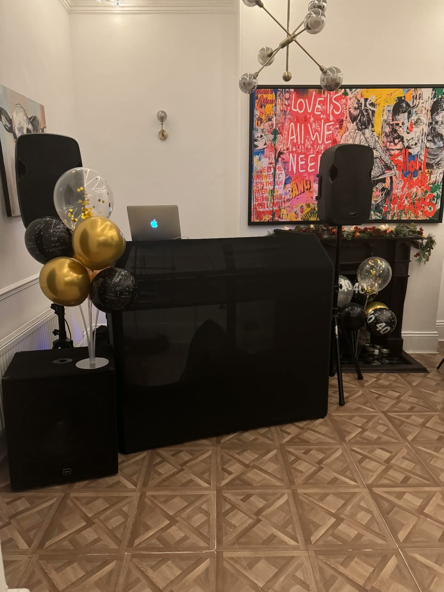 Black DJ booth setup with gold and black birthday balloons and speaker